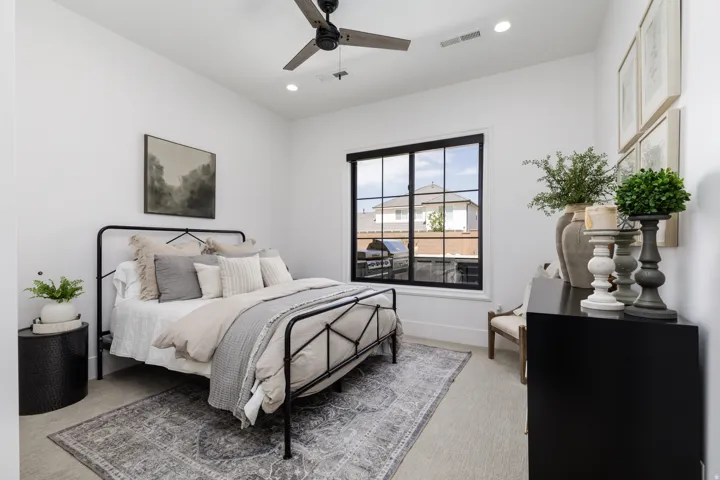 Recessed lighting, ceiling fan, large window with black framing, wood-finish flooring, and white walls