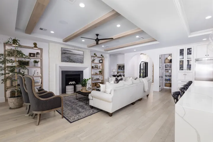 Recessed lighting, wood-finish flooring, fireplace with stone surround, coffered ceiling with wood beams, and built-in shelving