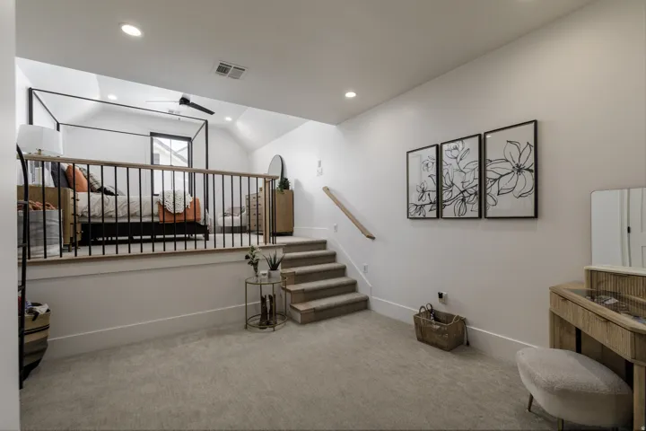 Carpeted flooring throughout, recessed lighting, and a loft space featuring a wood-finish railing with black metal spindles