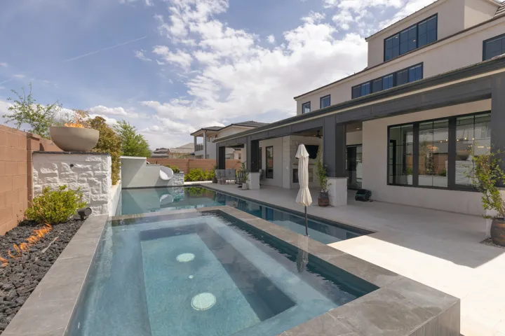 Backyard oasis featuring a swimming pool, integrated spa, and an adjacent covered patio