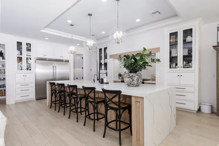 Gourmet kitchen featuring white cabinetry, a large center island with waterfall countertops, stainless steel appliances, and wood-finish flooring