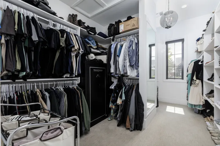 Custom closet system featuring multiple hanging rods, integrated shelving, and carpet flooring