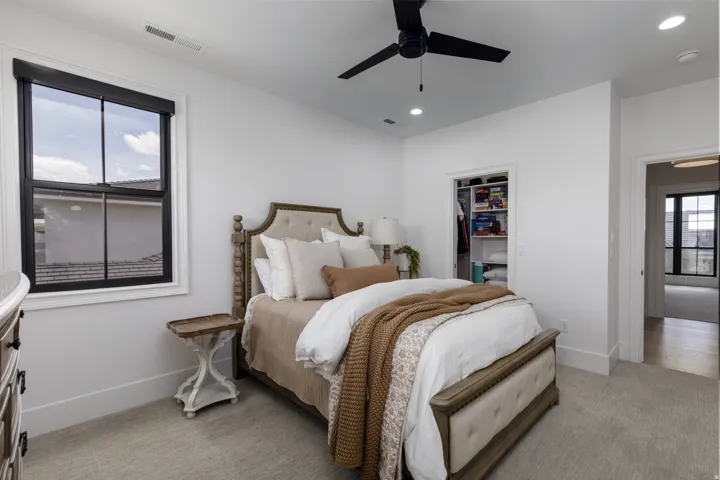 Plush carpeting, a built-in closet with shelving, recessed lighting, and a ceiling fan