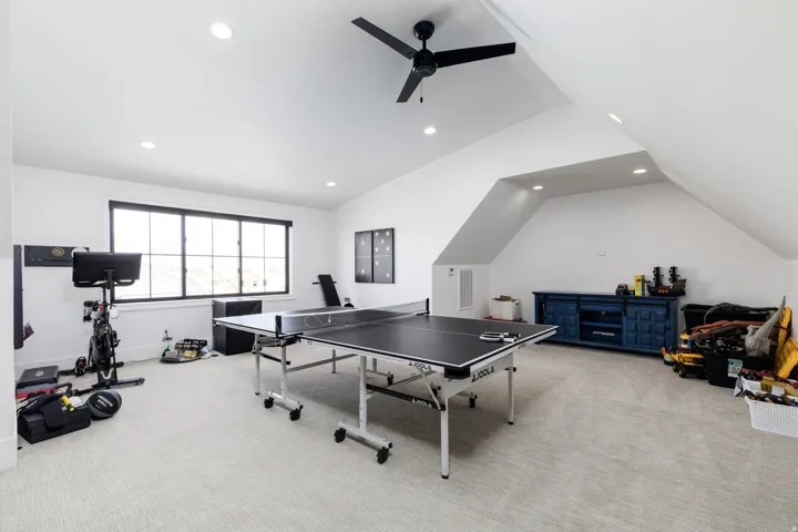 Spacious bonus room featuring vaulted ceilings, recessed lighting, a modern ceiling fan, and large black-framed windows
