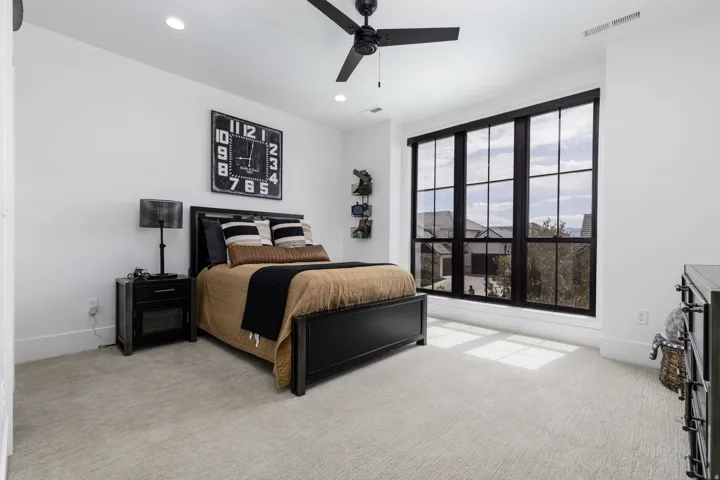 Expansive window with black grid framing, recessed ceiling lighting, ceiling fan, and light-toned carpet flooring