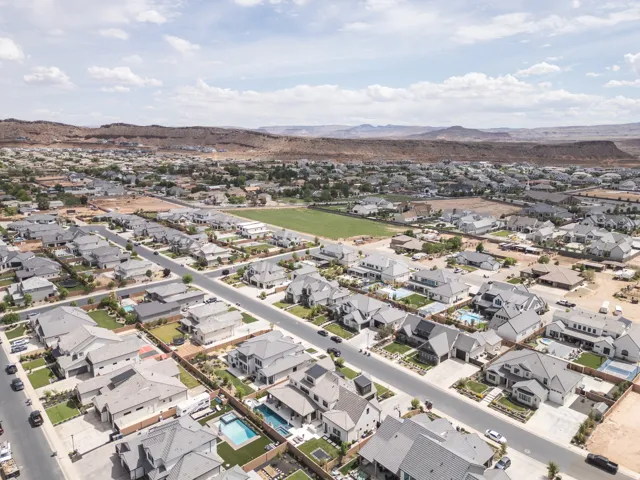 Residential street featuring single-family homes with pitched roofs, front landscaping, and attached garages
