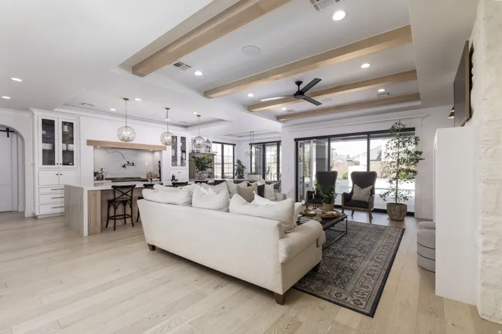 Open-concept living area with light wood-finish flooring, a coffered ceiling with wood beams, and recessed lighting