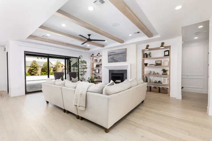 Wood-finish flooring, coffered ceiling with light wood beams, recessed lighting, and a modern ceiling fan