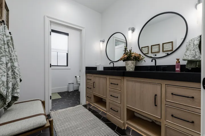 Dual vanity with light wood-finish cabinetry and matte black hardware
