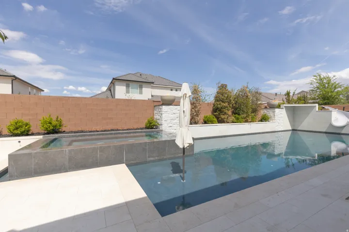 Backyard oasis featuring a swimming pool, integrated spa, adjacent patio, and a water slide feature