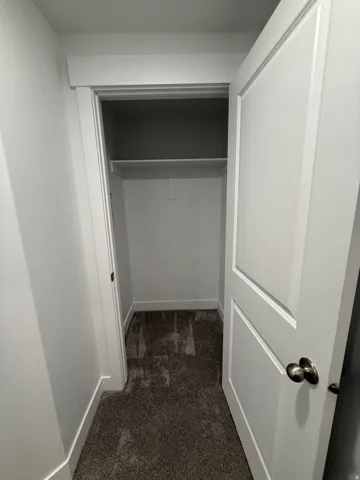 Recessed closet with a single shelf, panel door, and brushed nickel hardware