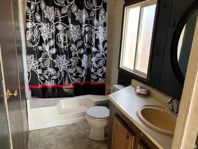 Bathroom featuring a built-in tub/shower combination, window with privacy glass, vanity with an integrated sink, and an oval wall mirror