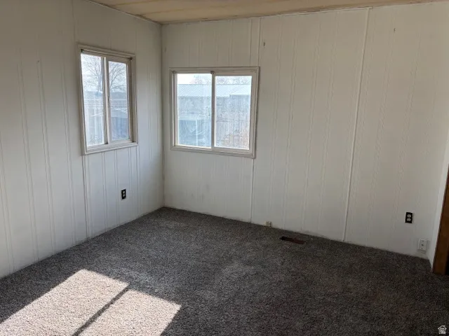 Textured wall panels, two windows, wood-finish ceiling, and carpeted flooring