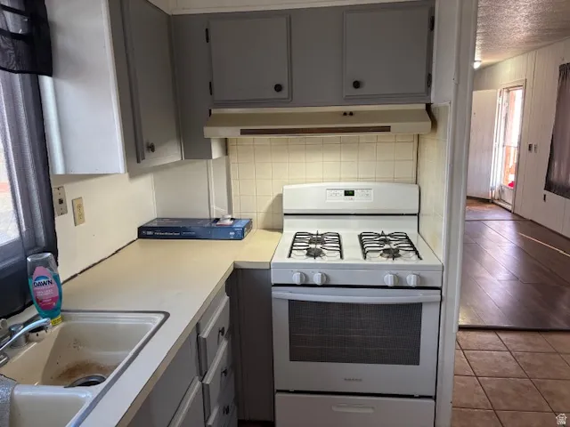 Kitchen featuring a built-in gas range, tile backsplash, upper and lower cabinetry, and an integrated sink