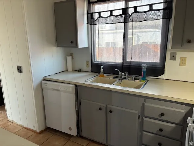 Dual basin sink with a chrome faucet, white paneled walls, and tiled flooring