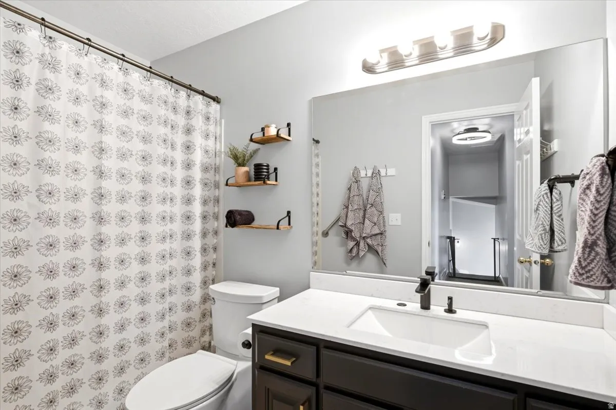 Vanity with an integrated sink, quartz countertop, dark wood-finish cabinetry, and matte black faucet