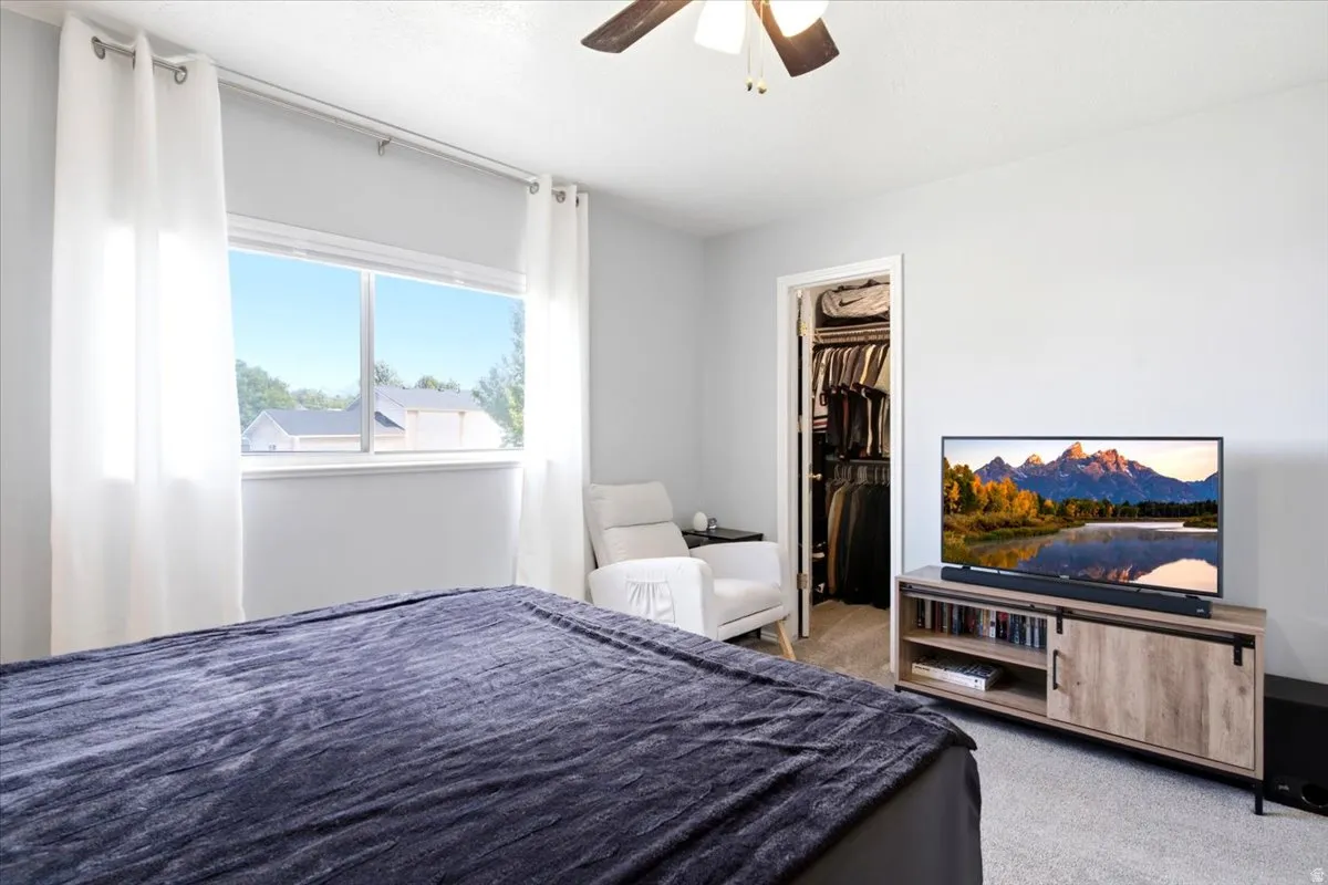 Carpeted flooring, ceiling fan, window with white trim, and a built-in closet