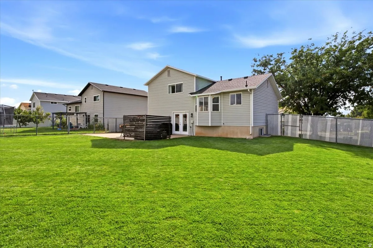 Expansive yard featuring a large grassy area, a concrete patio, and a horizontal slat privacy screen