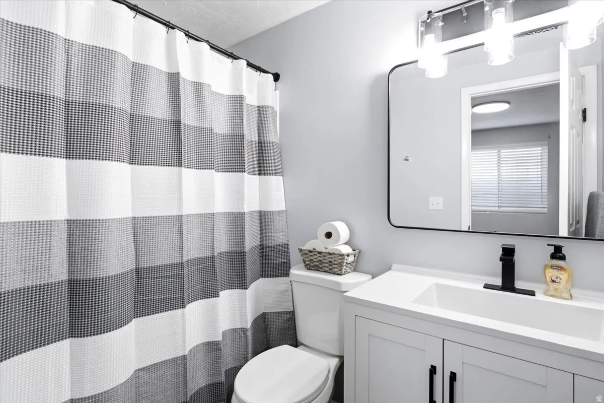 White vanity with black hardware, rectangular undermount sink, and matte black faucet