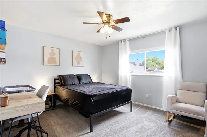 Carpeted flooring, ceiling fan with integrated lighting, window with ample natural light, light-toned wall paint, and white trim