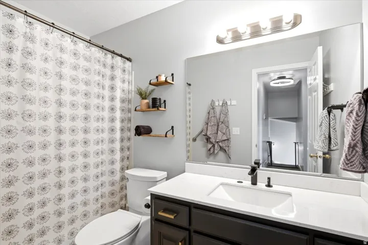 Vanity with an integrated sink, quartz countertop, dark wood-finish cabinetry, and matte black faucet