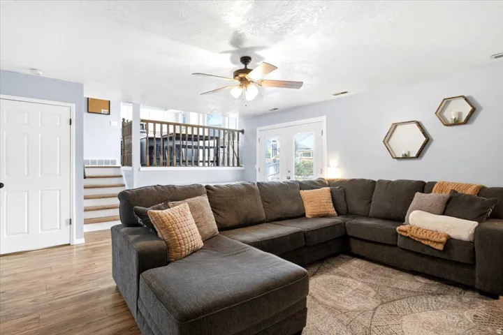 Wood-finish flooring, white paneled door, ceiling fan, and double French doors to the exterior