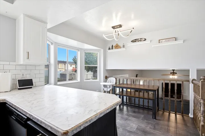 Kitchen featuring white upper cabinetry, subway tile backsplash, and a bay window