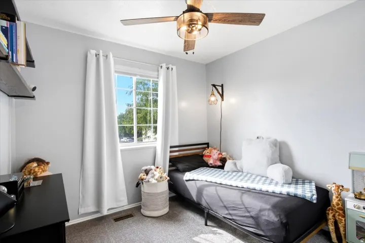 Recessed window with white trim, ceiling fan with wood-finish blades, wall-mounted light fixture, and gray wall color