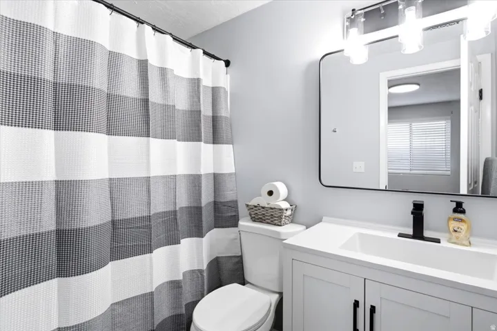 White vanity with black hardware, rectangular undermount sink, and matte black faucet