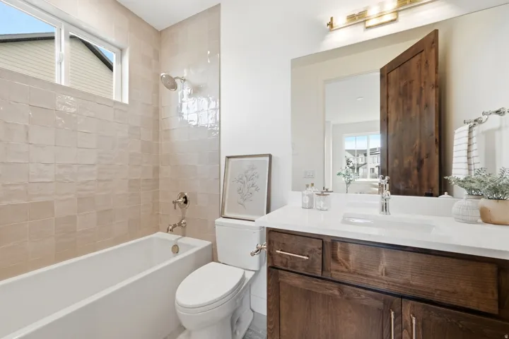 White bathtub with polished chrome fixtures and textured tile surround
