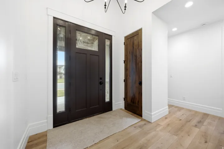Dark wood-finish entry door with clear glass sidelights, light wood-finish flooring, and recessed ceiling lighting