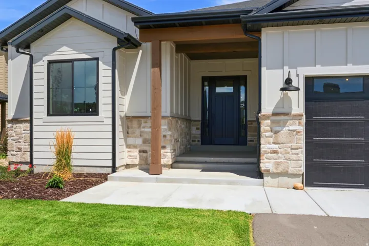 Contemporary exterior featuring horizontal siding, board and batten accents, a stone veneer foundation, and a dark paneled front door