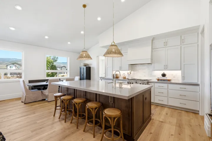 Spacious kitchen featuring a large central island with seating, light wood-finish flooring, white cabinetry, and recessed lighting
