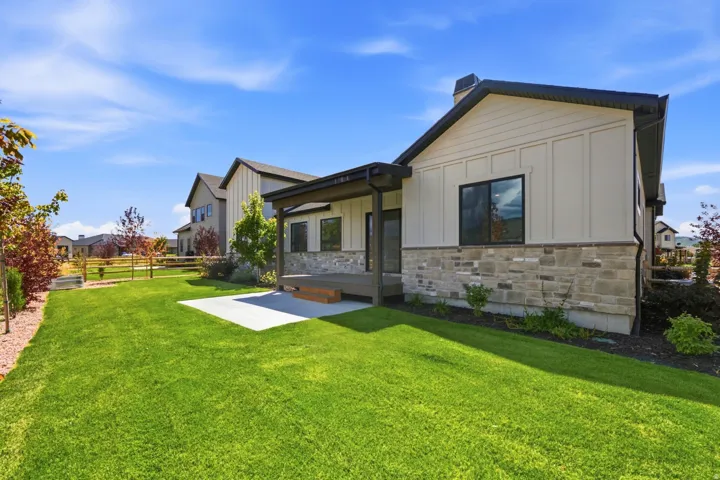 Expansive backyard featuring a manicured lawn, a concrete patio, a covered wooden deck, and a wooden fence