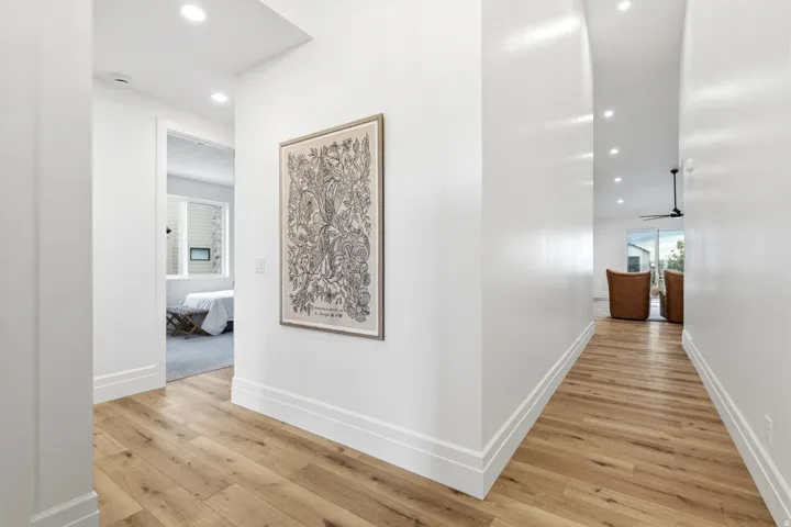 Wood-finish flooring throughout, bright white walls, recessed ceiling lighting, and a ceiling fan