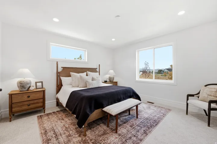 Recessed lighting illuminates a space featuring a large window, a horizontal transom window, and light-toned carpeting