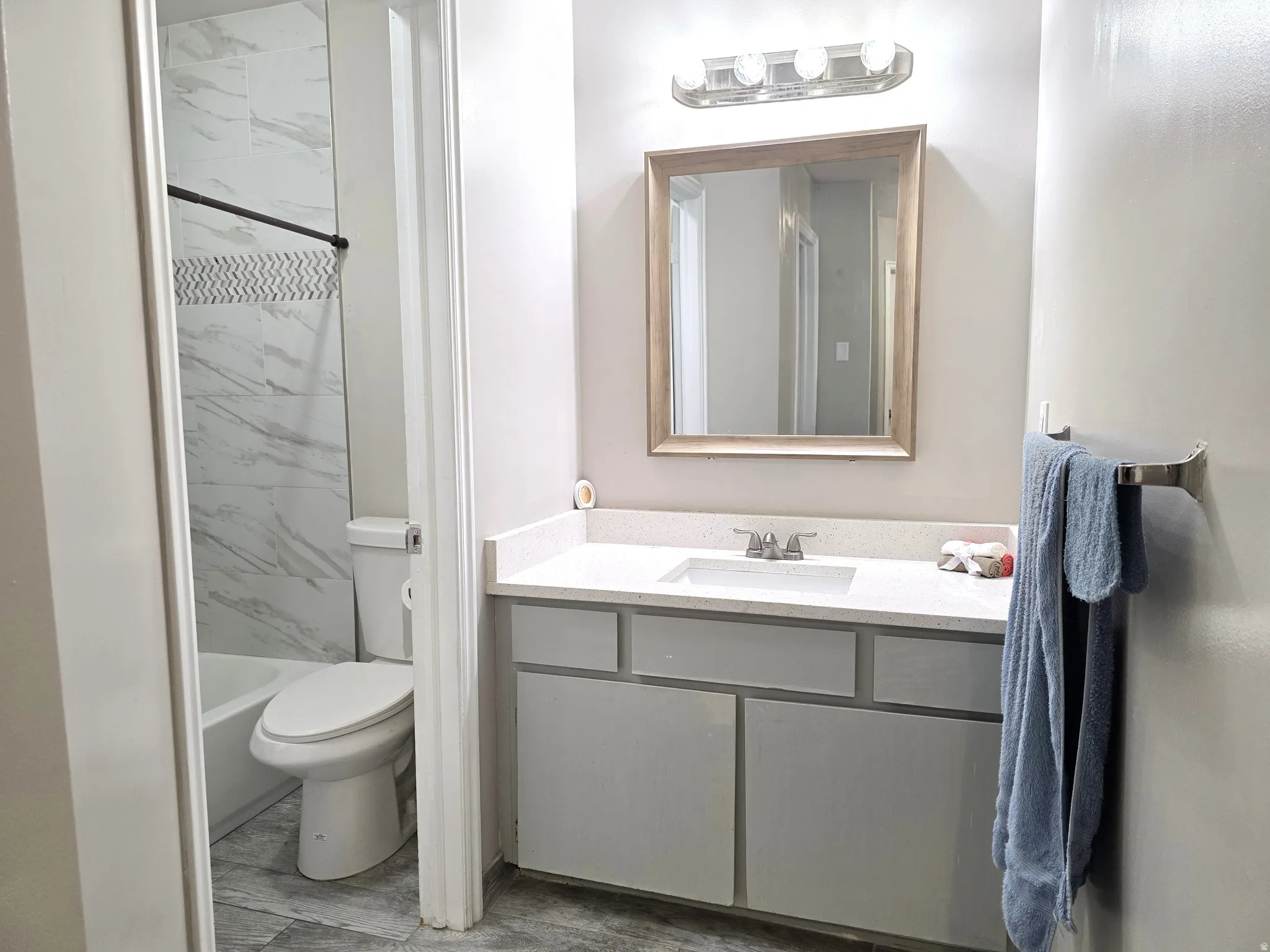 Vanity with a light-colored countertop, framed mirror, and a four-light fixture