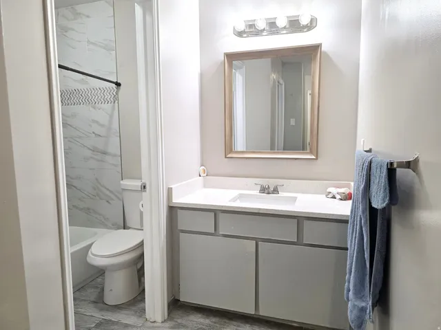 Vanity with a light-colored countertop, framed mirror, and a four-light fixture