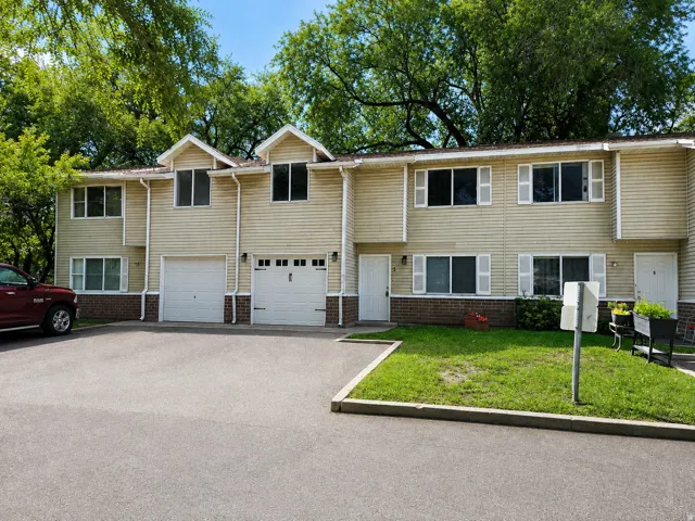 Two-story townhome with light-colored siding and a brick foundation