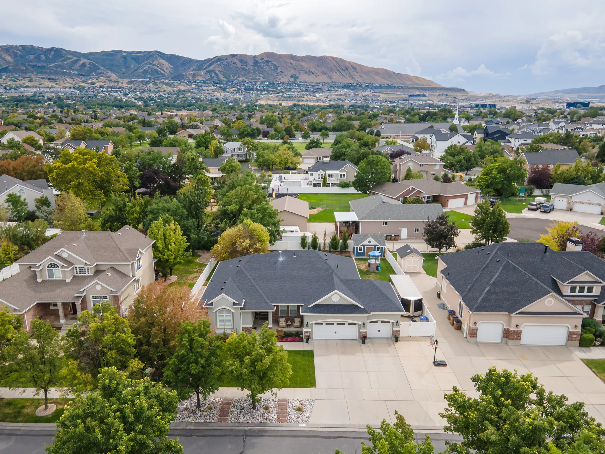 Expansive lot featuring a multi-car driveway, attached garage, and mature landscaping