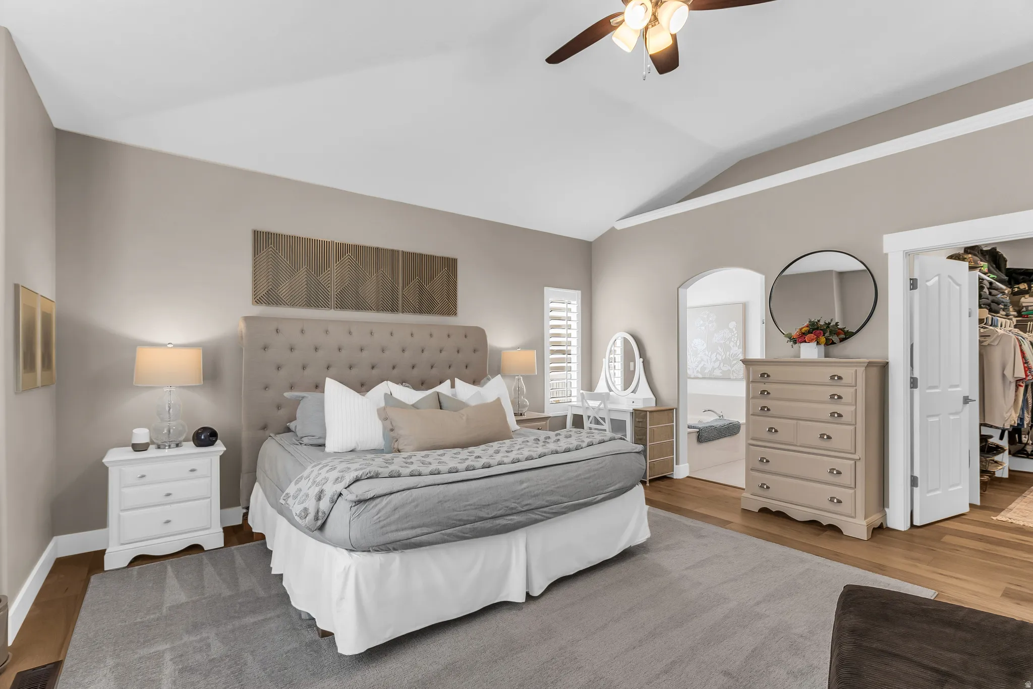 Vaulted ceilings with a ceiling fan, plush carpet, hardwood flooring, and an arched doorway