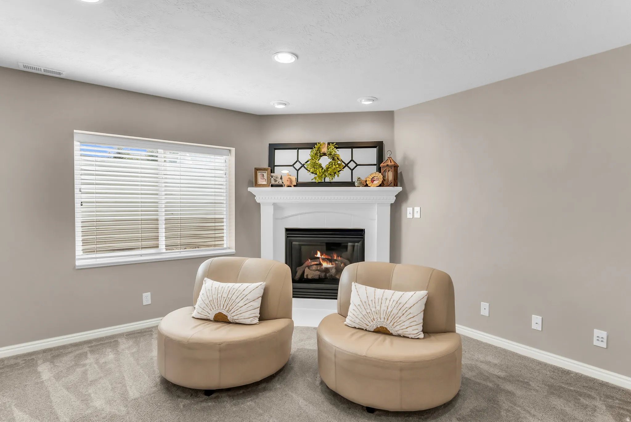 Built-in fireplace with a white mantel, recessed lighting, neutral wall paint, white window blinds, and gray carpet flooring