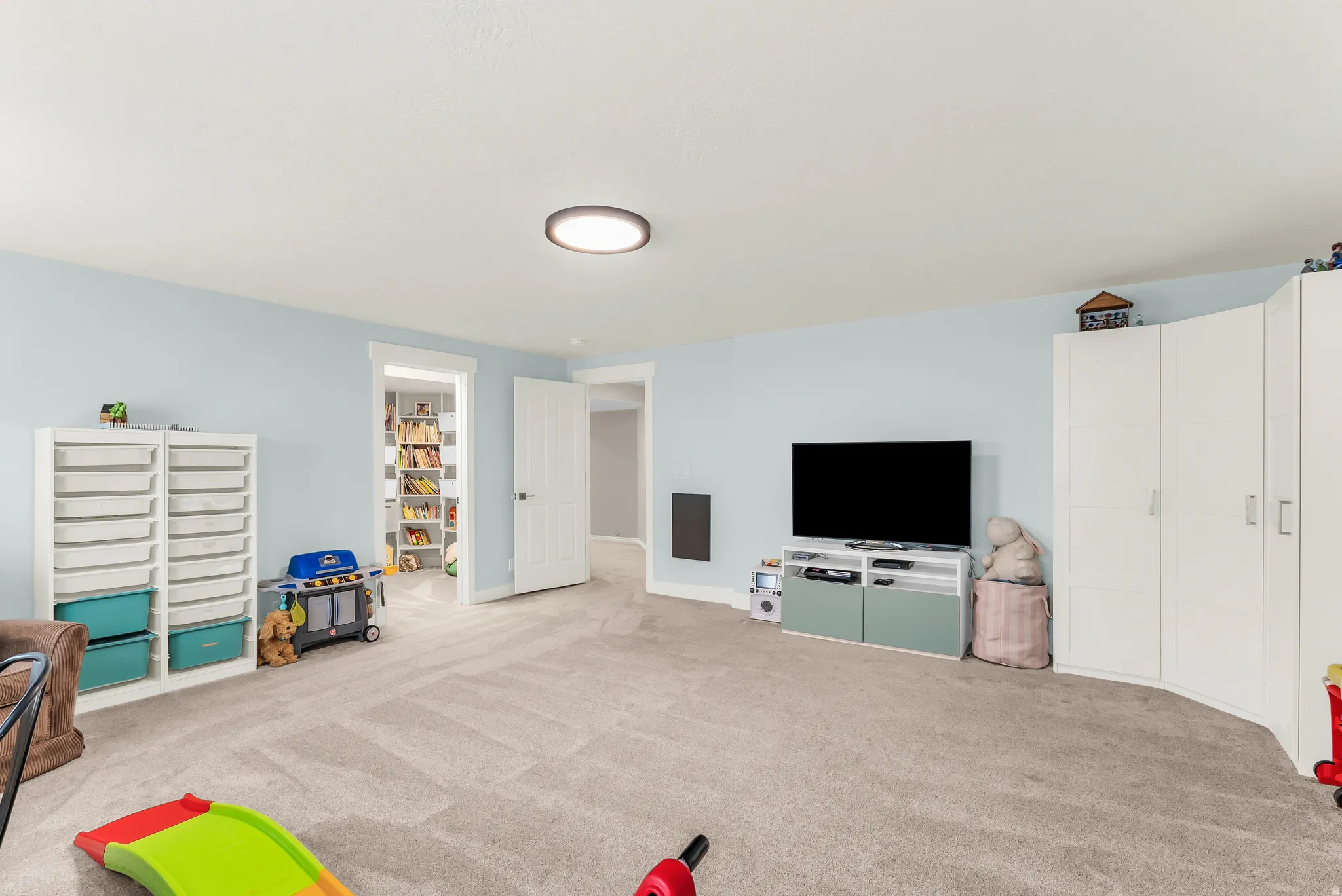 Recessed ceiling light, light-toned carpeting, and a built-in wall unit with shelving