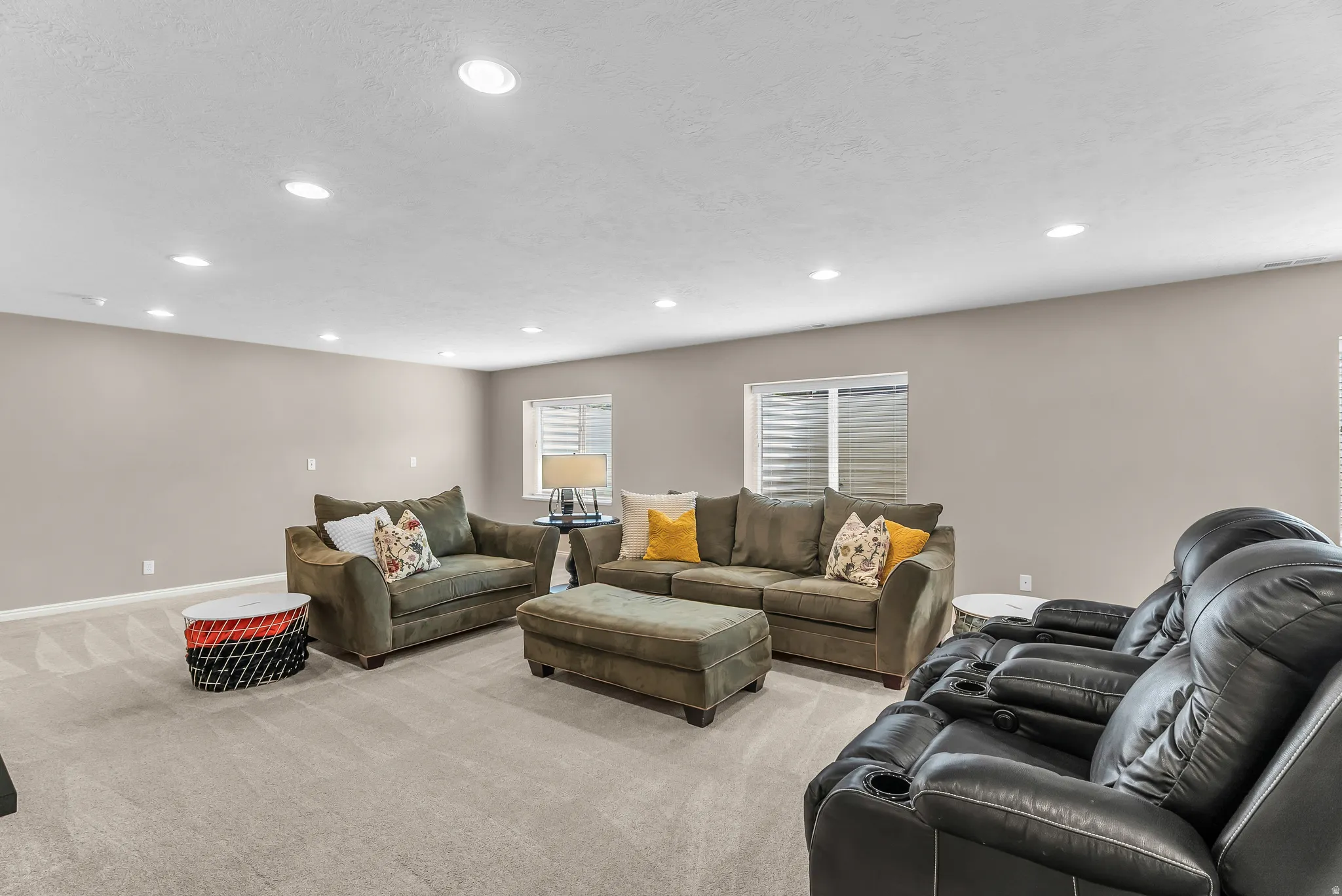Recessed lighting illuminates this expansive space featuring neutral wall tones and plush carpet flooring