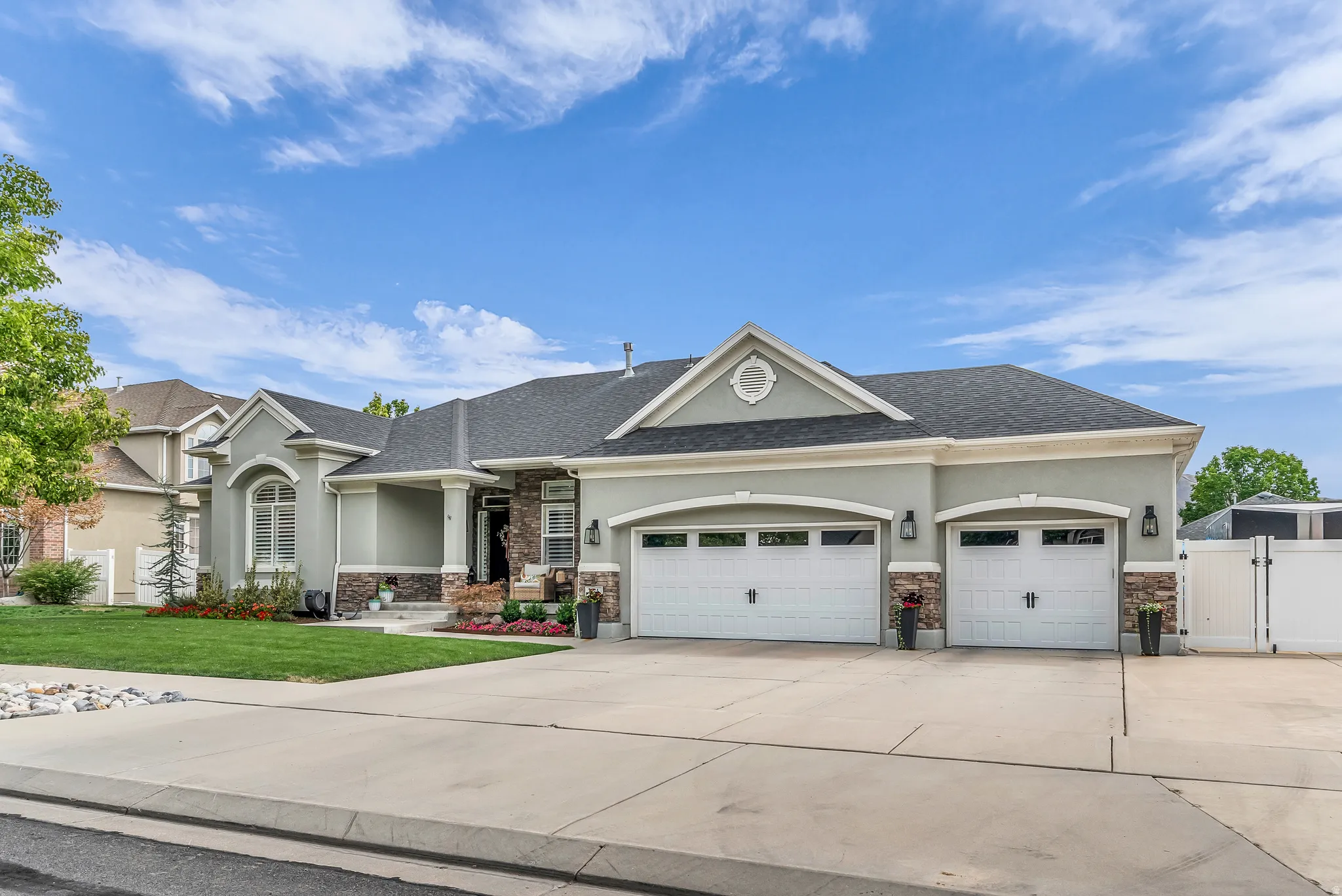 Stucco exterior with stone accents, covered entry, arched windows, and a multi-car garage with carriage-style doors