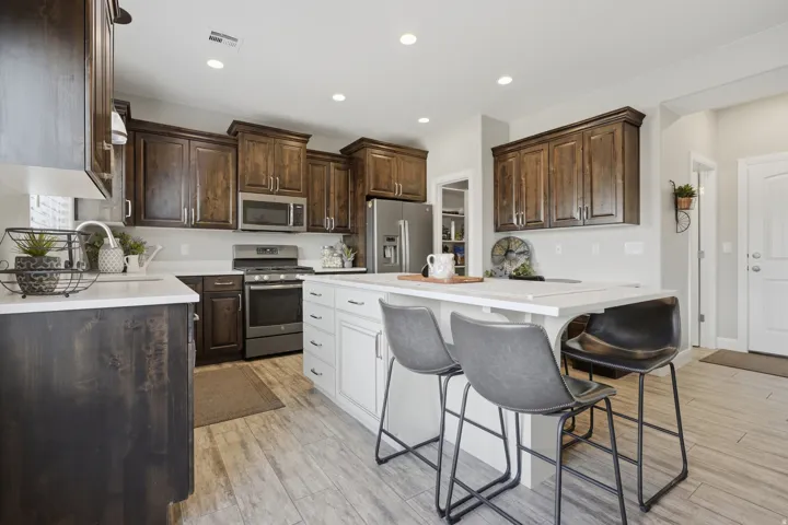 Kitchen featuring dark wood cabinetry, stainless steel appliances, a center island with seating, light countertops, and wood-finish flooring