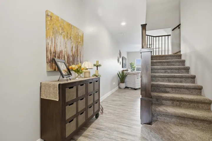 Wood-finish flooring, recessed lighting, carpeted staircase, and dark wood and iron balusters