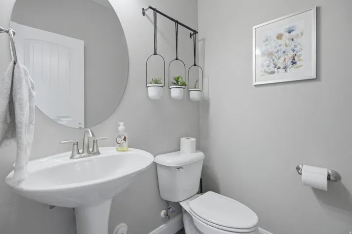 Guest bathroom. Pedestal sink with a brushed nickel faucet, and  round wall-mounted mirror.