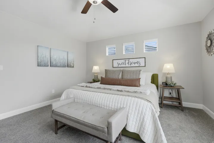 Master bedroom with Vaulted ceiling featuring a ceiling fan, light gray wall paint, three transom windows with blinds, and gray carpet flooring