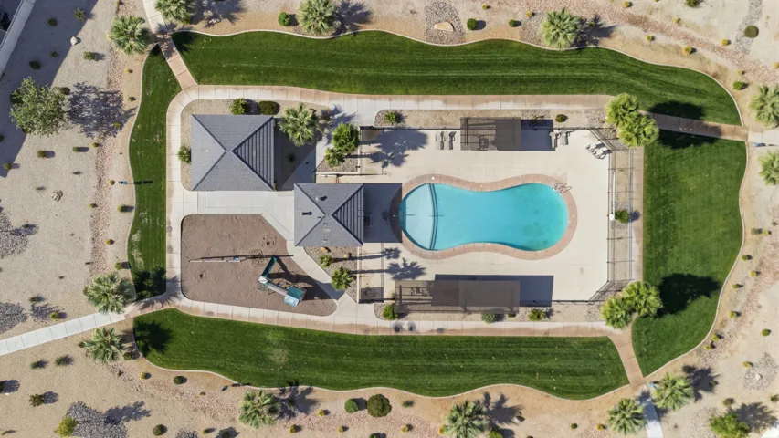 Community amenity area featuring a swimming pool, shaded seating, a playground, and two covered structures